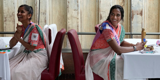 Zwei indische Frauen sitzen an Tischen