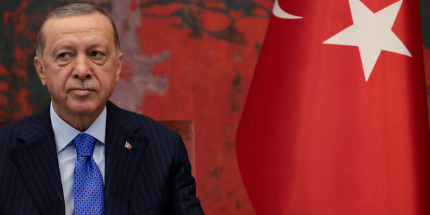 Präsident Recep Tayyip Erdoğan neben einer Türkei-Flagge