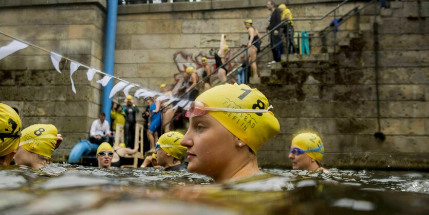 Menschen mit Badekappen im Wasser an der Museumsinsel