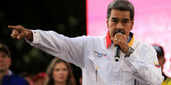 Nicholas Maduro hält ein Mikrofon und zeigt mit dem rechten Arm in eine Richtung