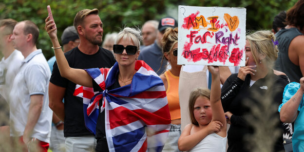 Eine Frau hat sich in eine britische Fahne gewickelt, neben ihr ein Mädchen mit Plakat 