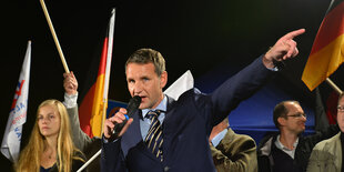 Höcke spricht in das Mikro vor Deutschlandflaggen