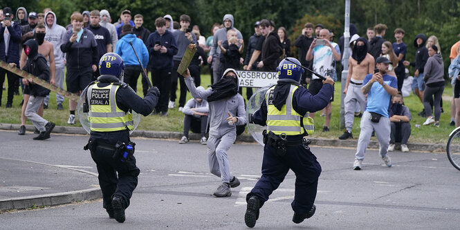 Ein jugendlicher Randalierer wirft einen Teil eines Zauns auf Polizisten während einer Demonstration gegen Einwanderung in der Nähe des Holiday Inn Express Hotel, in dem Asylbewerber untergebracht sind.