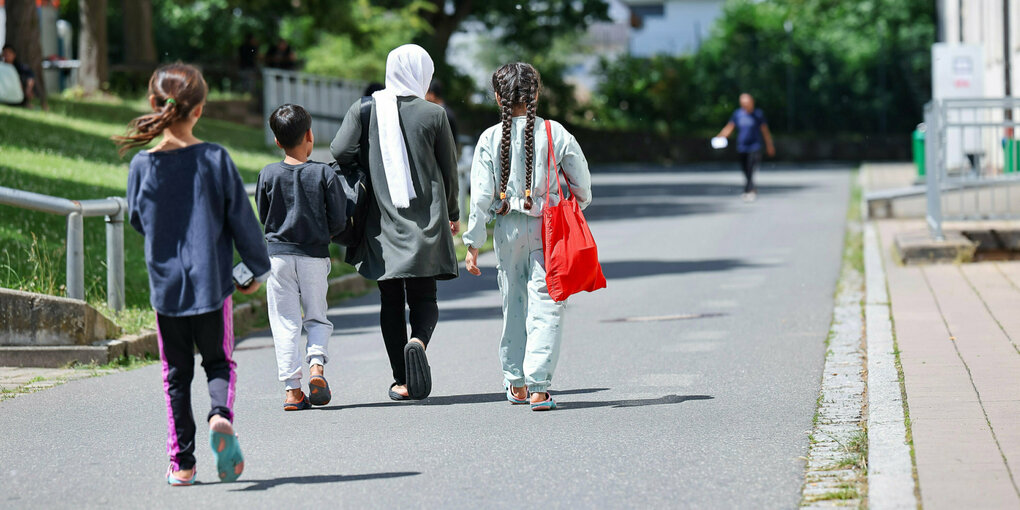 Eine Frau geht mit 3 Kindern über einen WEg