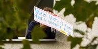 Aus dem Fenster einer Wohnung hält eine Person ein Schild mit der Aufschrift "Nazis verpisst euch keiner vermisst euch"