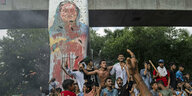 Demonstranten jubeln am Montag in Dhaka neben einem Portrait von Sheikh Hasina über deren Flucht aus dem Land