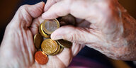 Die Hände einer älteren Person mit Geldmünzen.