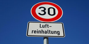 An einem Verkehrschild mit der Geschwindigkeitsbegrenzung von 30 kmh befindet sich ein Zusatzschild mit dem Schriftzug Luftreinhaltung.