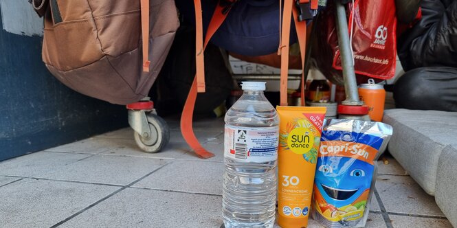 Wasser, Sonnencreme und Capri-Sonne vor dem Lager einer obdachlosen Person.