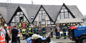 Zahlreiche Einsatzkräfte der Feuerwehr, des Technischen Hilfswerks und des Deutschen Roten Kreuzes laufen in Einsatzkleidung vor einem Fachwerkhaus herum, das teilweise eingestürzt ist