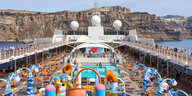 Ein Kreuzfahrtschiff mit Urlaubern vor der Insel Santorin in Griechenland