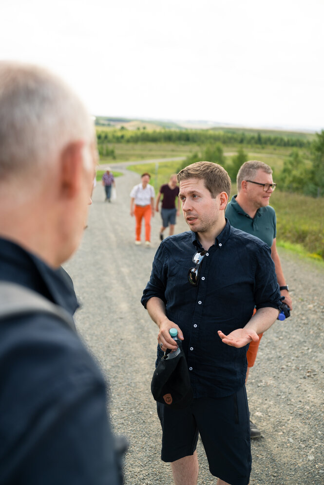 Ein Mann unterhält sich mit anderen Teilnehmer:innen einer Wanderung.