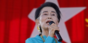 Aung San Suu Kyi spricht in ein Mikrofon