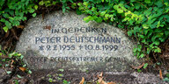 Ein Gedenkstein mit der Aufschrift "In Gedenken - Peter Deutschmann" liegt auf dem Gelände einer Kirche.