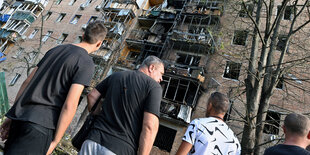 Menschen vor einem zerstörten Wohnhaus in Kursk