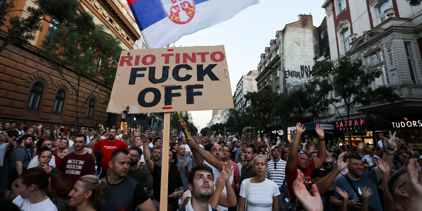 Demonstration mit vielen Menschen, eine Person hält ein Schild hoch auf dem "Rio Tinto Fuck Off" steht