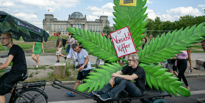 Teilnehmer der Hanfparade ziehen ein Modell eines Cannabisblattes.