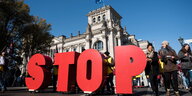 Demonstranten mit großen roten "STOP"-Buchstaben