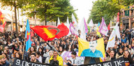 viele Menschen auf einer Straße mit Fahnen und einem Bild von Öcalan