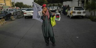 Ein Straßenverkäufer steht auf der Straße mit Flaggen der Taliban