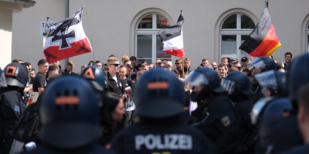 Teilnehmer einer rechten Demonstration mit Fahnen in Bautzen anlässlich des CSDs dort, im Vordergrund Polizisten