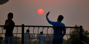 Mann recht Smartphone für Selfie in den Sonnenuntergang