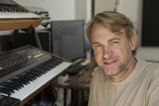 Ein Mann mit blonden Haaren sitzt vor einem Keyboard