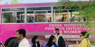 Passanten vor und Fahrgästinnen in einem Pink Bus, Aufschrift: Prime Minister Pink Bus Initiative For Women