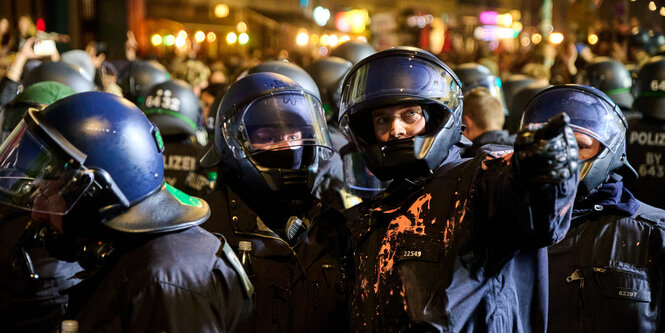 Polizisten in Schutzkleidung, die mit Farbe bekleckert ist