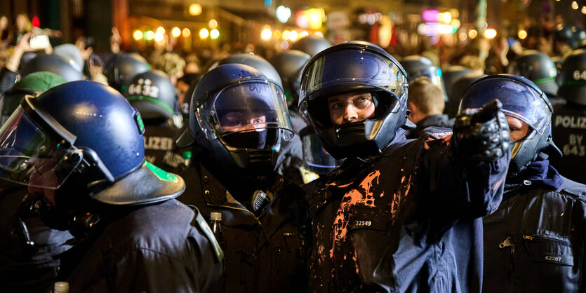 Polizisten in Schutzkleidung, die mit Farbe bekleckert ist