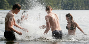 Vier junge Leute stehen im Wasser und spitzen sich nass