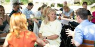 Petra Köpping sitzt in eiem Biergarten, umringt von Menschen, die ihr zuhören. Sie lächelt