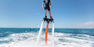 Eine Person fliegt auf einem Flyboard über die Wasseroberfläche