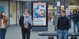 Ein Fahndungsplakat, auf dem Burkhard Garweg abgebildet ist in der Fußgängerzone einer Innenstadt