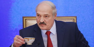 Alexander Lukaschenko drinkt eine Tasse Kaffee während einer Konferenz.