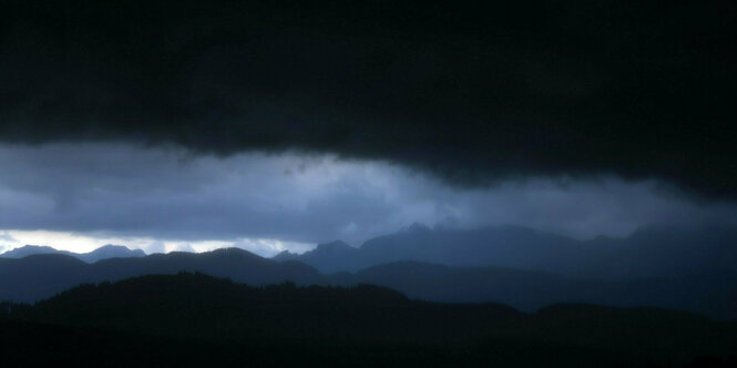 Dunkle Wolken liegen über einer Berglandschaft