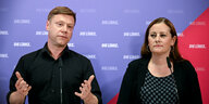 Janine Wissler und Martin Schirdewan stehen an einem Tisch