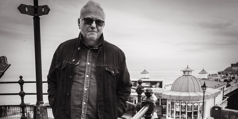 Wreckless Eric in Blackpool, im Hintergrund sieht man Fahrgeschäfte eines Rummelplatzes