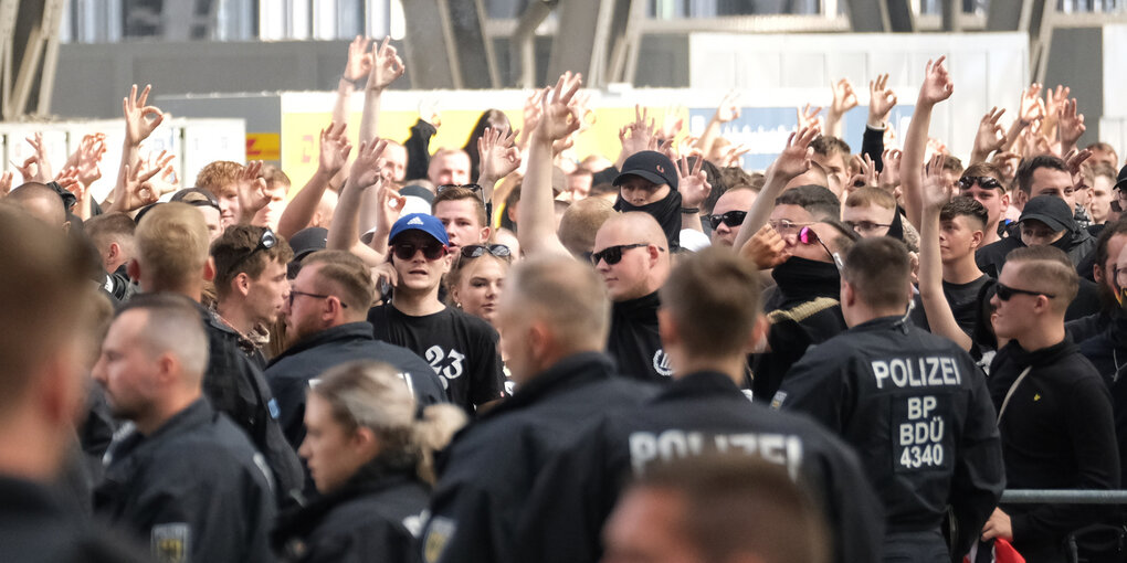 Eine Gruppe Nazis von der Polizei umgeben halten den Arm in die Luft und machen das White Power Zeichen