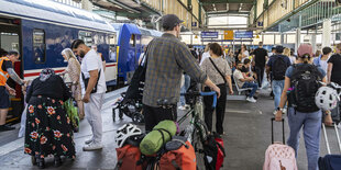 Menschen mit Reisegepäck auf einem Bahnhof