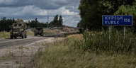 Militärfahrzeuge auf einer Landstraße, rechts im Bild ein Straßenschild, das Kursk mit 108 Kilometer anzeigt.