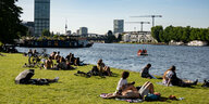 Menschen liegen auf der Wiese am Spreeufer