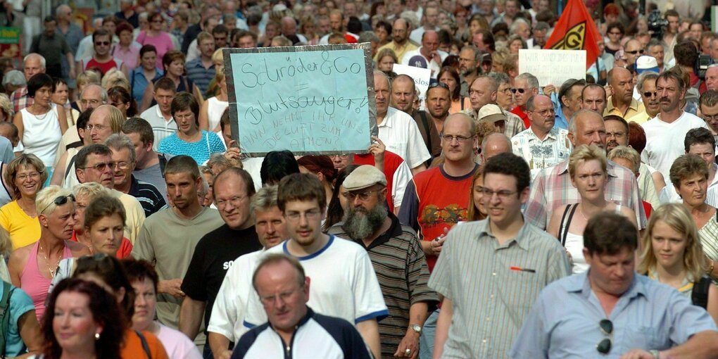 Zahlreiche Teilnehmer einer Demonstration ziehen mit Schildern gegen Hartz IV in Erfurt in einem langen Zug zur Staatskanzlei