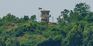 Auf einem grünen Hügel steht ein Wachhäuschen auf dem eine nordkoreanische Flagge weht