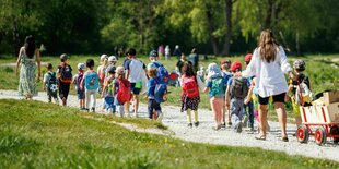 Eine Kindergruppe geht begleitet von zwei Erzieherinnen durch den Park