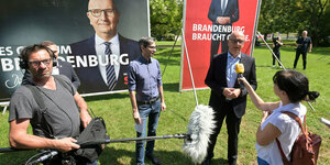 Woidke vor Wahlplakaten wird von Journalisten befragt