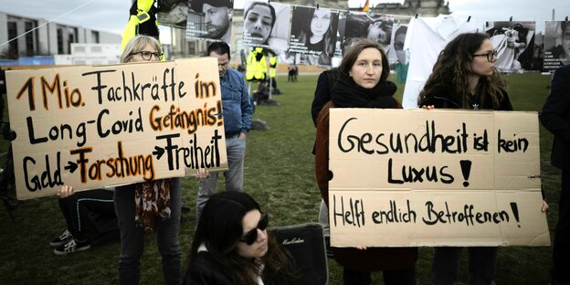 Menschen demonstrieren mit Schildern vor dem Deutschen Bundestag