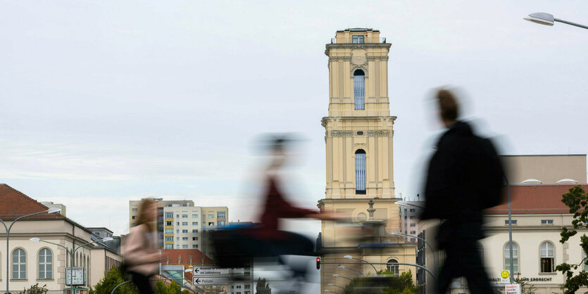 Passanten (Bewegungsunschärfe) sind vor dem Turm der Garnisonkirche in der Innenstadt unterwegs.