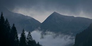 Dunkle Wolken über Bergen.