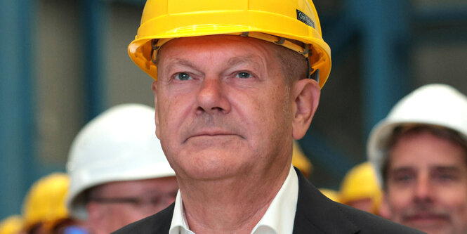 Olaf Scholz trägt einen gelben Bauhelm